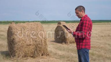 智慧生活方式<strong>农耕</strong>农业理念.. 一个工人农民在数字平板电脑上的田野里研究干草堆。 慢慢
